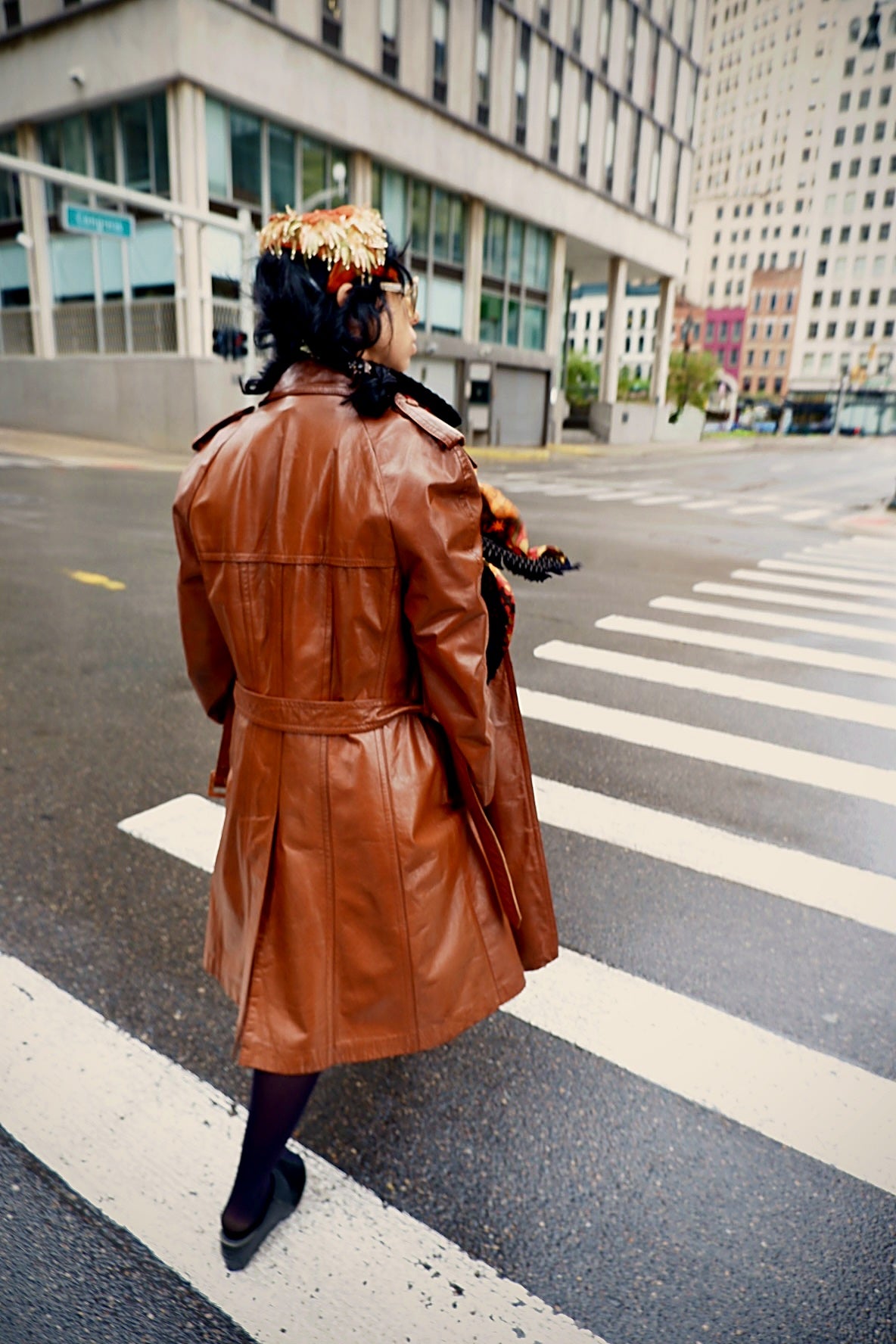 Model crossing the street in a vintage cognac leather trench coat