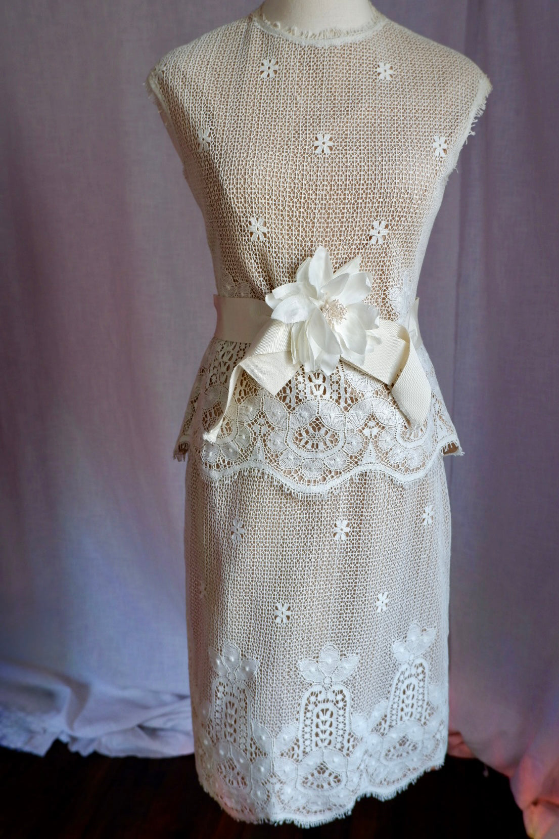 1960s ivory lace peplum top and pencil skirt set with silk flower sash on a dress form