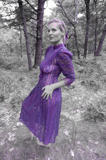Model in a 1980s plum lace Victorian-revival maxi dress posing in a pine forest (artistic color edit)
