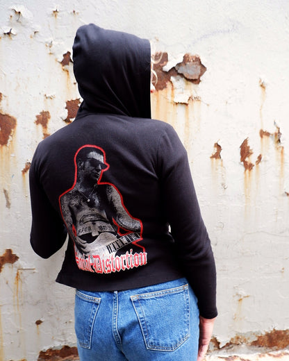 Black Social Distortion hoodie worn hood up, back print against peeling white paint