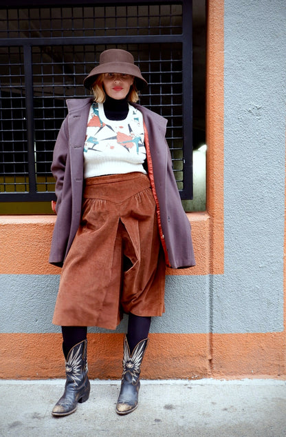 Model in a 1980s Brittany oversized mauve wool coat over rust corduroy culottes and cowboy boots