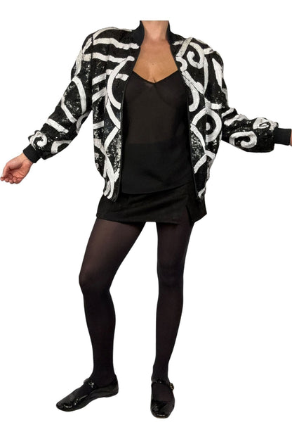 Laurence Kazar sequin bomber jacket worn open over a black top, arms out to show sleeves