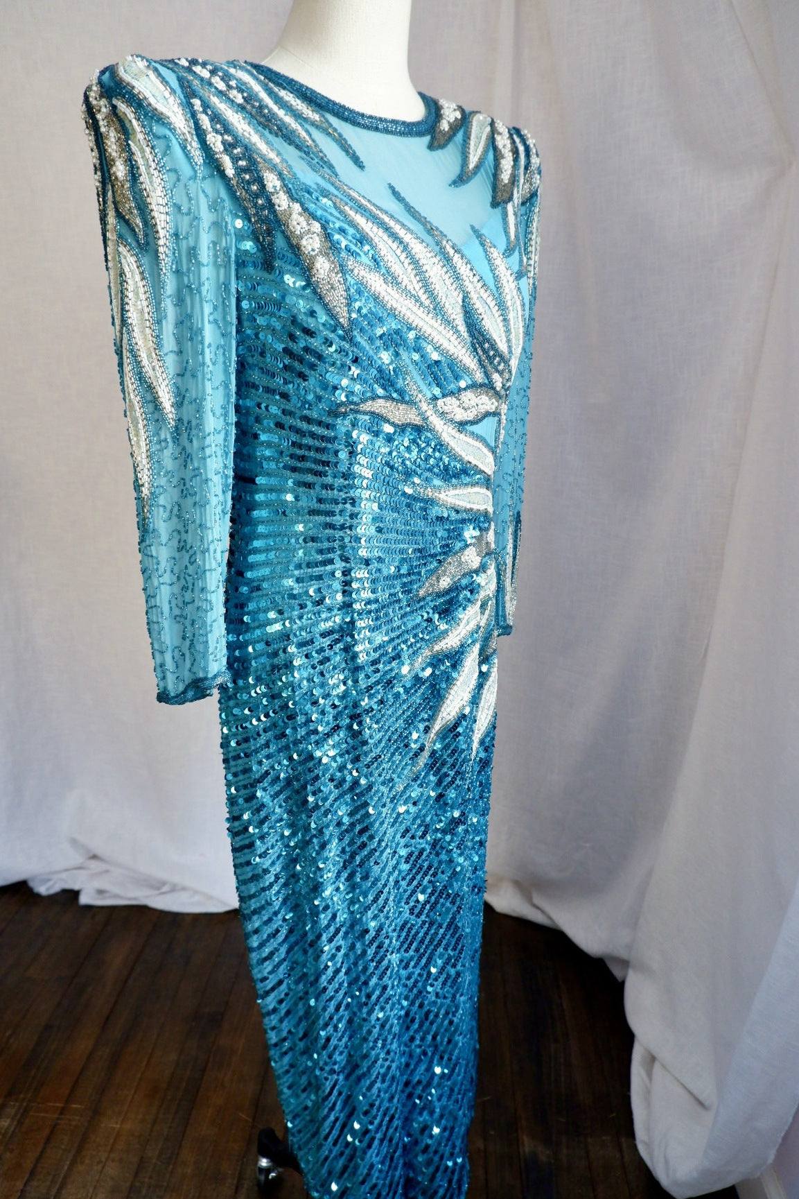 Full-length front three-quarter view of vintage turquoise beaded sequin gown with padded shoulders