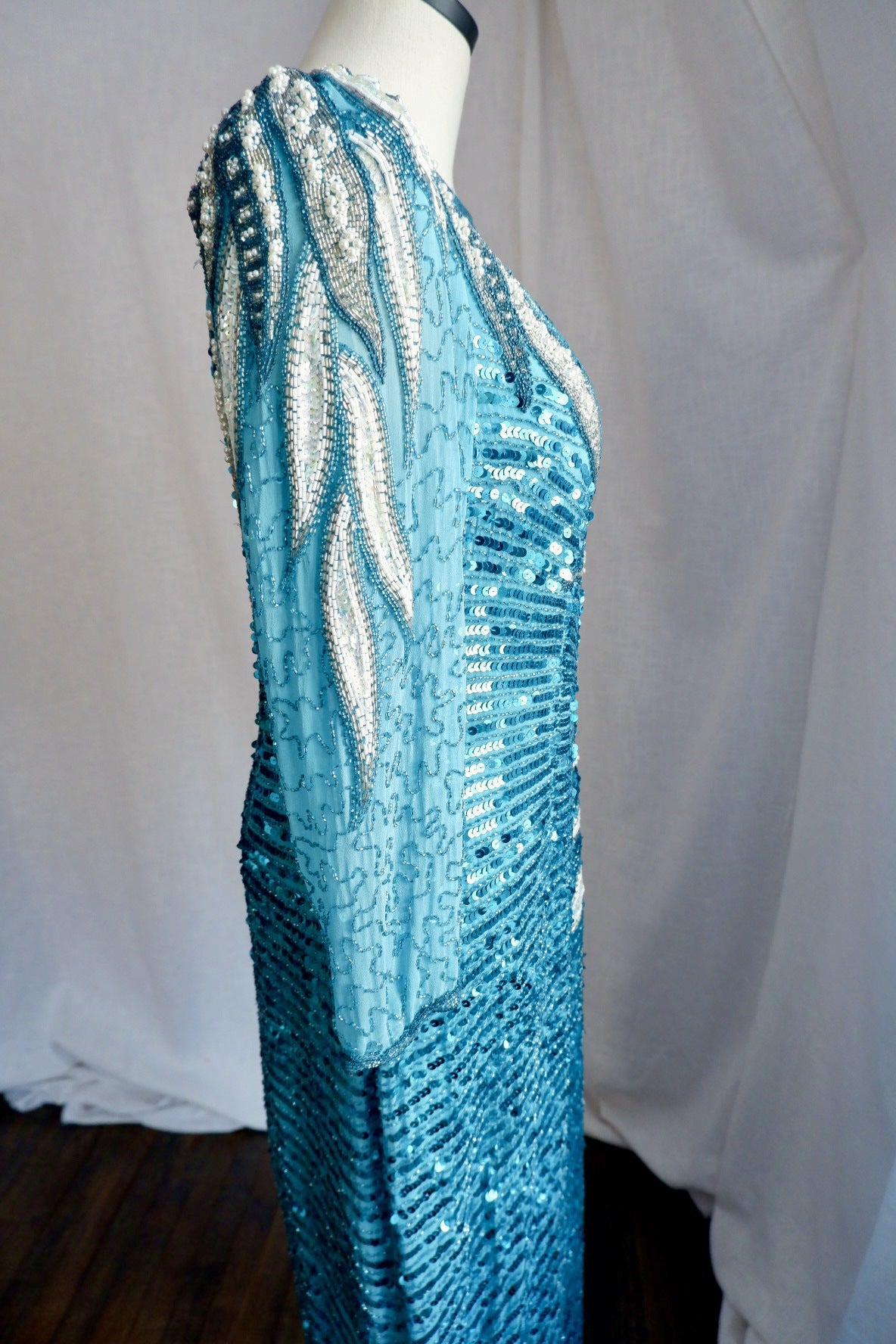 Side view of 1980s turquoise sequin gown showing sheer beaded sleeve and leaf beadwork