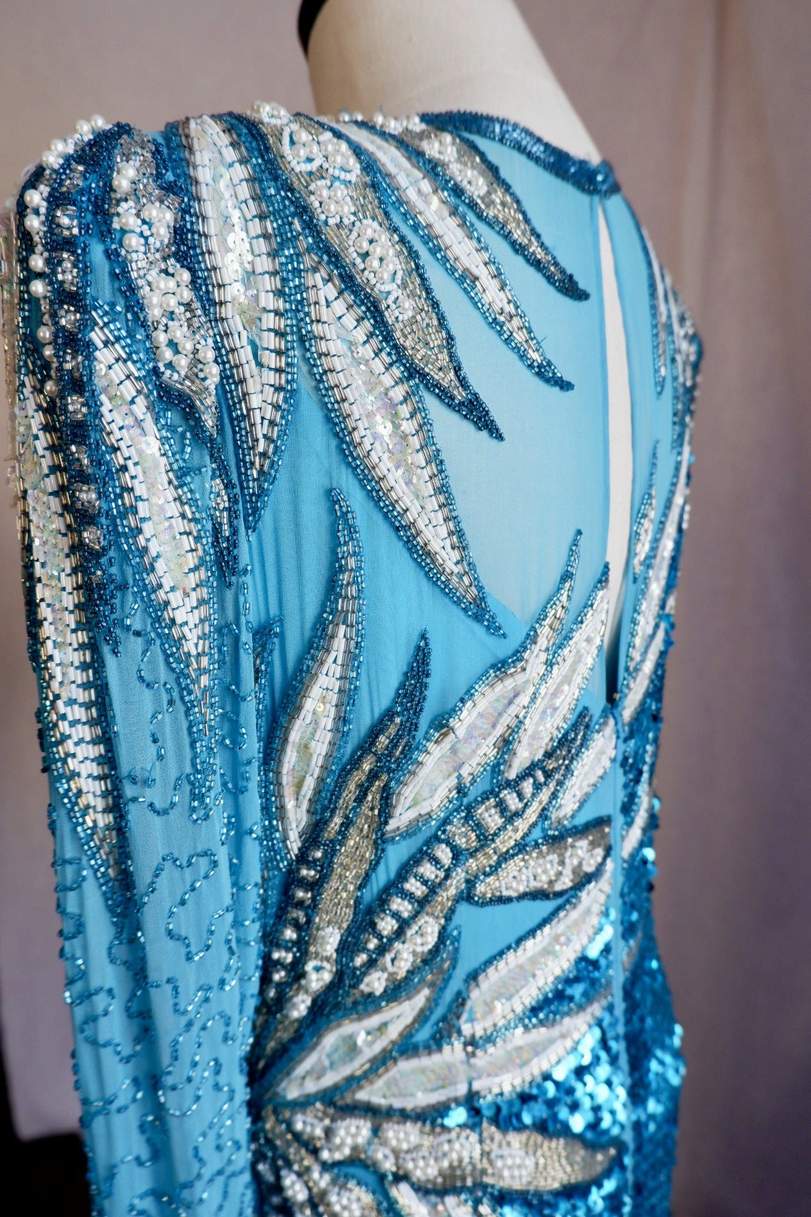 Shoulder detail of padded shoulder covered in faux pearls, bugle beads and iridescent sequins