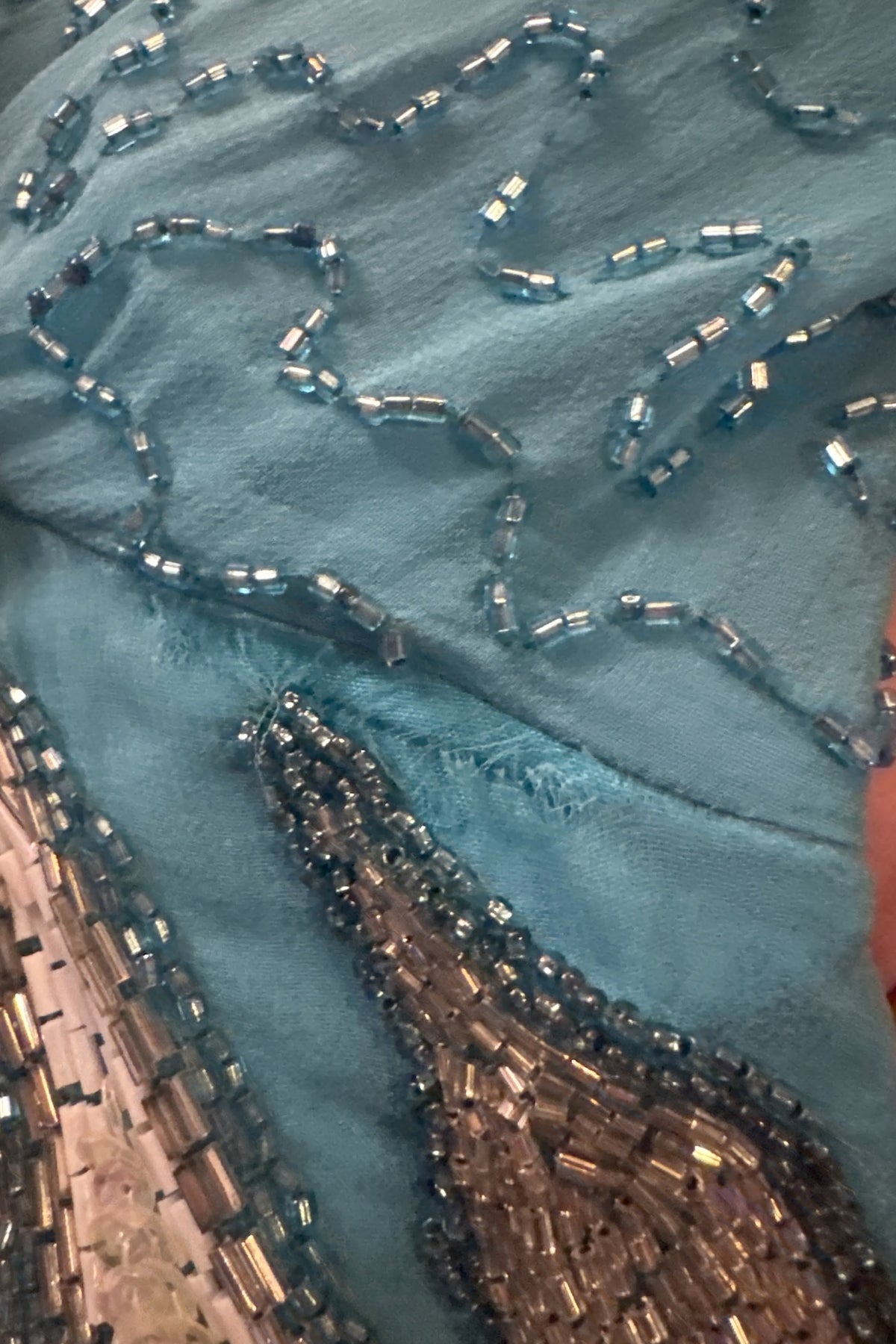 Small tear at the underarm seam of the beaded gown, shown for condition