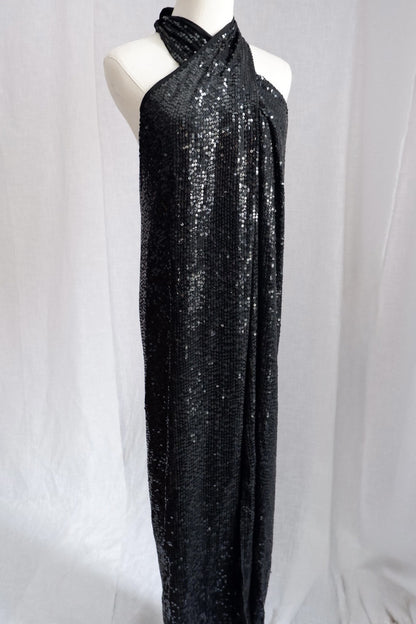 Angled front view of Donna Karan black sequin column gown with crossover halter neckline