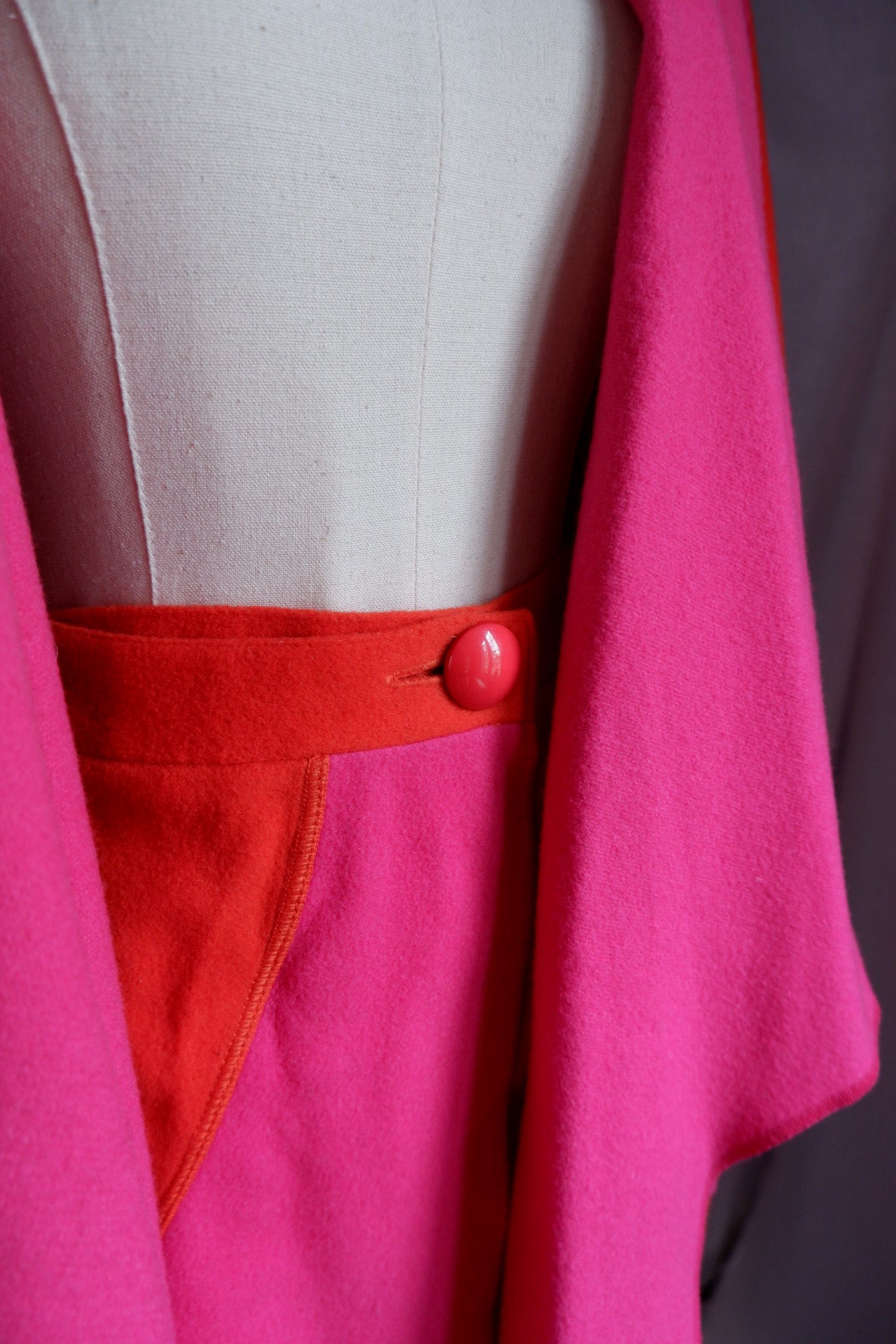 Close-up of Merle Chicago skirt orange waistband with round pink button and color-block hip panel