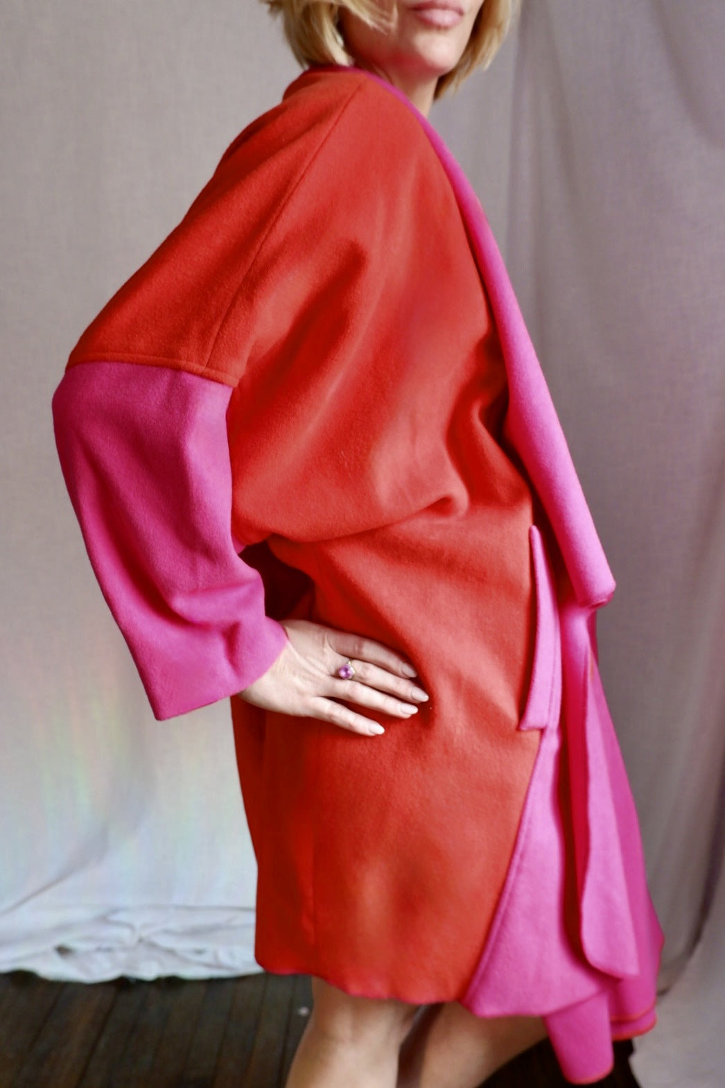 Side view of model in the Merle Chicago color-block wool coat showing orange body and pink sleeves