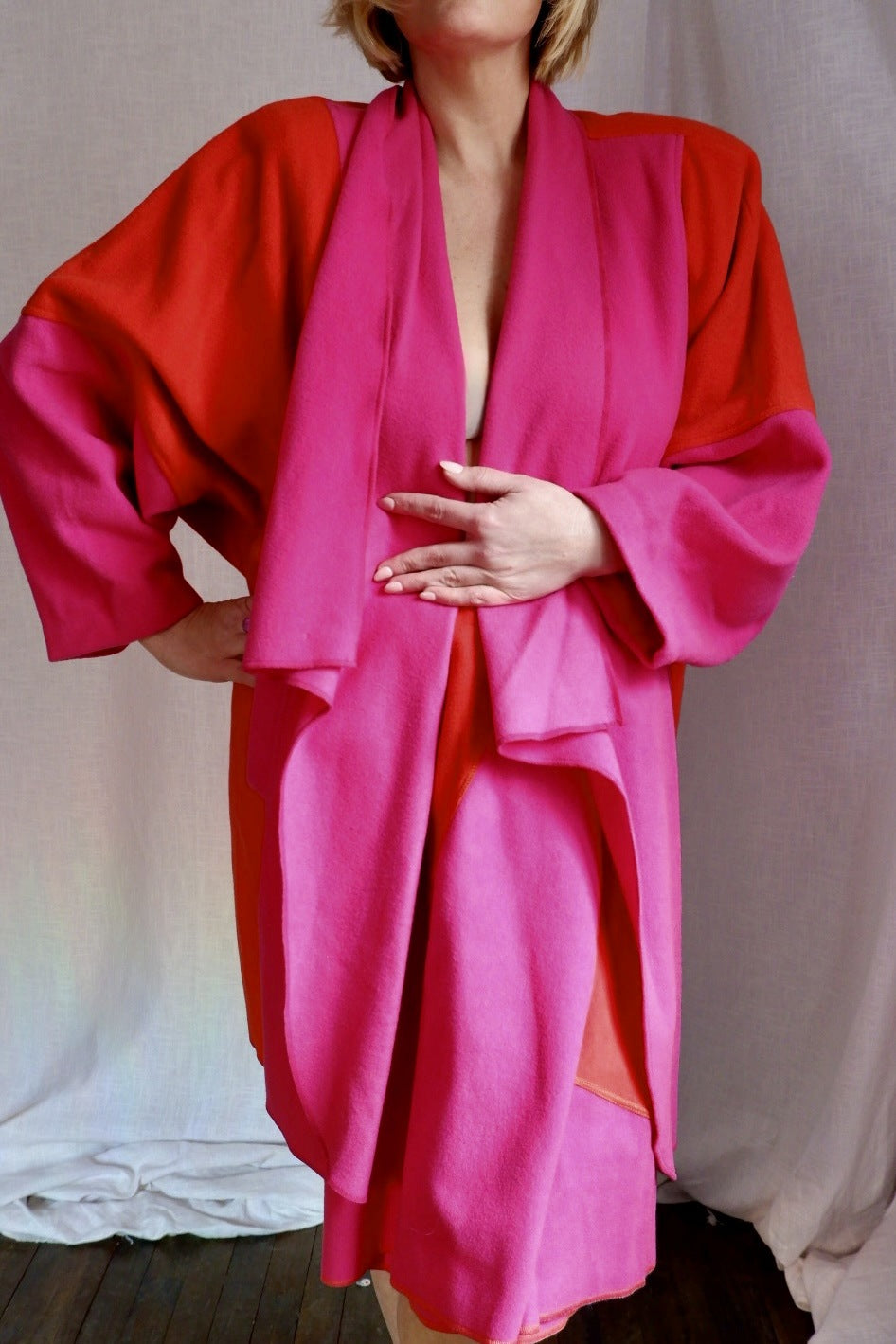 Model wearing the Merle Chicago pink and orange wool draped coat over the matching skirt
