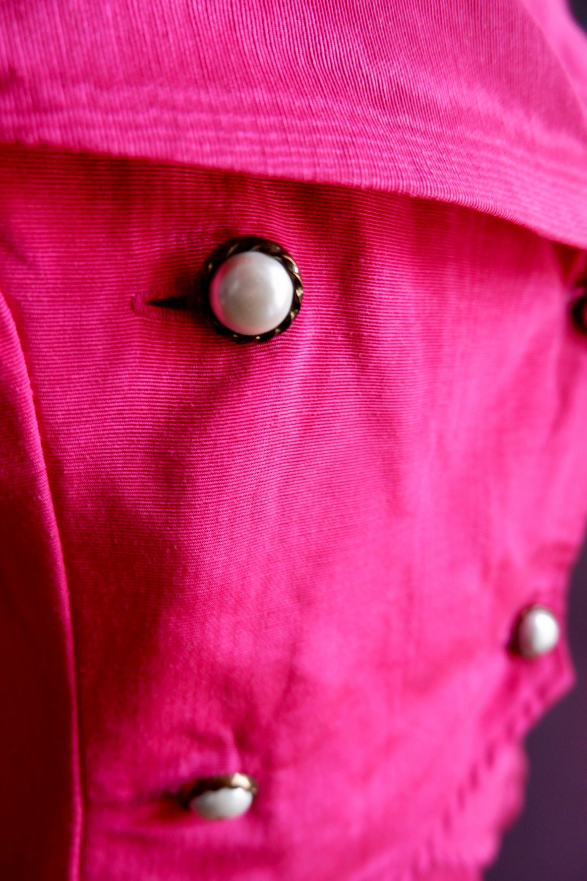 Close-up of pearl buttons in rope-twist metal settings on hot pink moiré jacket