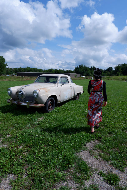 Quilted maxi dress walking toward a vintage car in a field