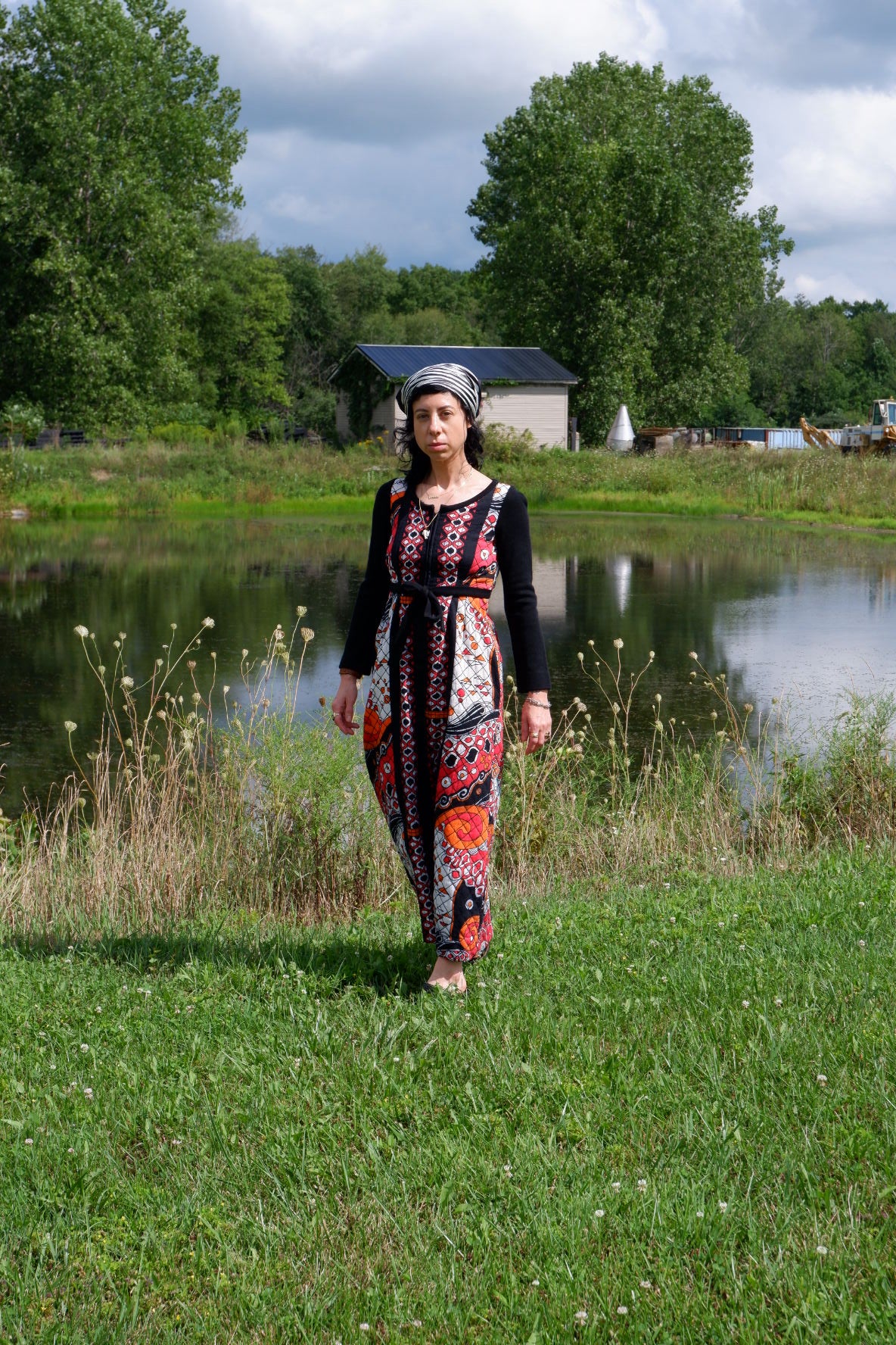 Quilted maxi dress with black knit sleeves and tie waist, front view by the water