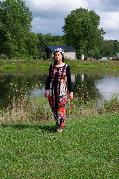 Quilted maxi dress with black knit sleeves and tie waist, front view by the water